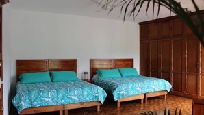 Una habitación con dos camas de madera con cabeceros a juego, un armario de madera grande y un suelo tejido.