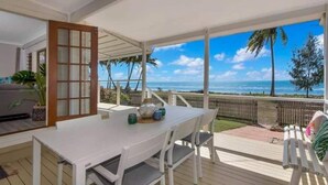 A covered patio with a table and chairs, a view of the ocean, and a wooden deck. - Amazing Oceanfront retreat at Saunders Beach (Saunders Beach)