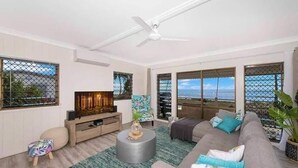 A modern living room with a sofa, a coffee table, and a TV. There are large windows with a view of the sea. - Amazing Oceanfront retreat at Saunders Beach (Saunders Beach)