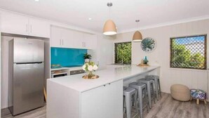 A modern kitchen with a central island, stainless steel refrigerator, pendant lights, and a window with a view. - Amazing Oceanfront retreat at Saunders Beach (Saunders Beach)