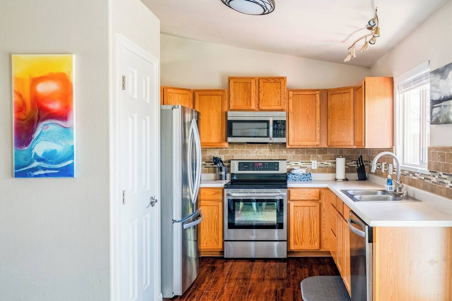 A modern kitchen with wooden cabinets, stainless steel appliances, and a tiled backsplash.