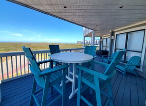 A covered outdoor area with a table and chairs, overlooking a grassy landscape and buildings in the distance. - Family friendly condo in Port Aransas (Port Aransas)