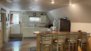 Une cuisine avec un îlot central en bois, des tabourets de bar et un réfrigérateur.