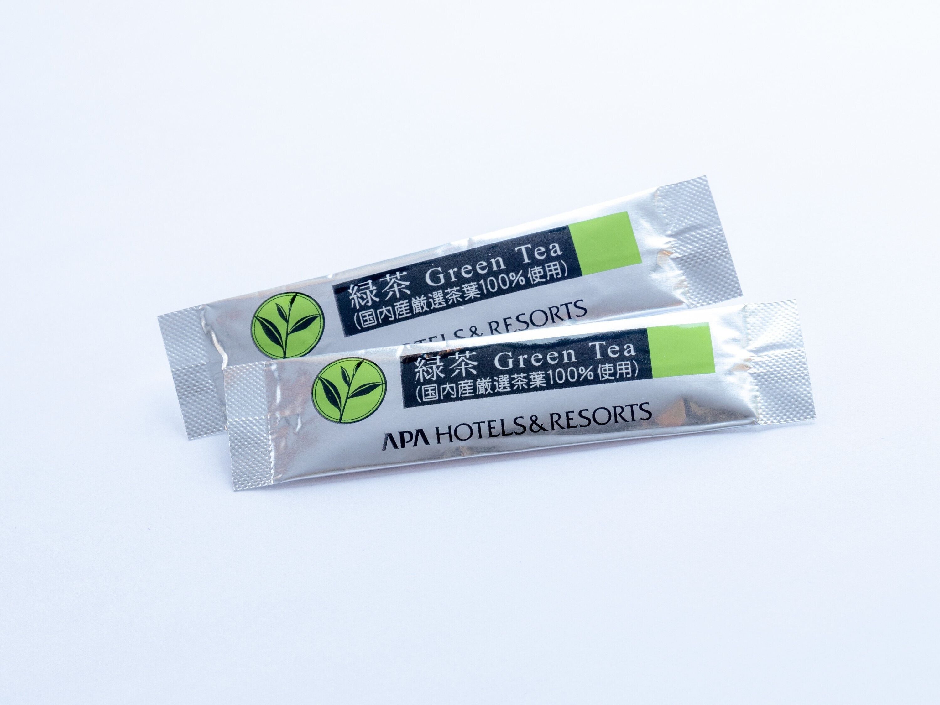 Two packages of green tea labeled for APA HOTELS&RESORTS.
