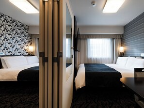 A hotel room with two beds, a large mirror, a TV, and a patterned wall.