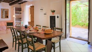 A dining area with a wooden table, green chairs, and a view of greenery outside. - Pergola by Interhome (Boccheggiano)