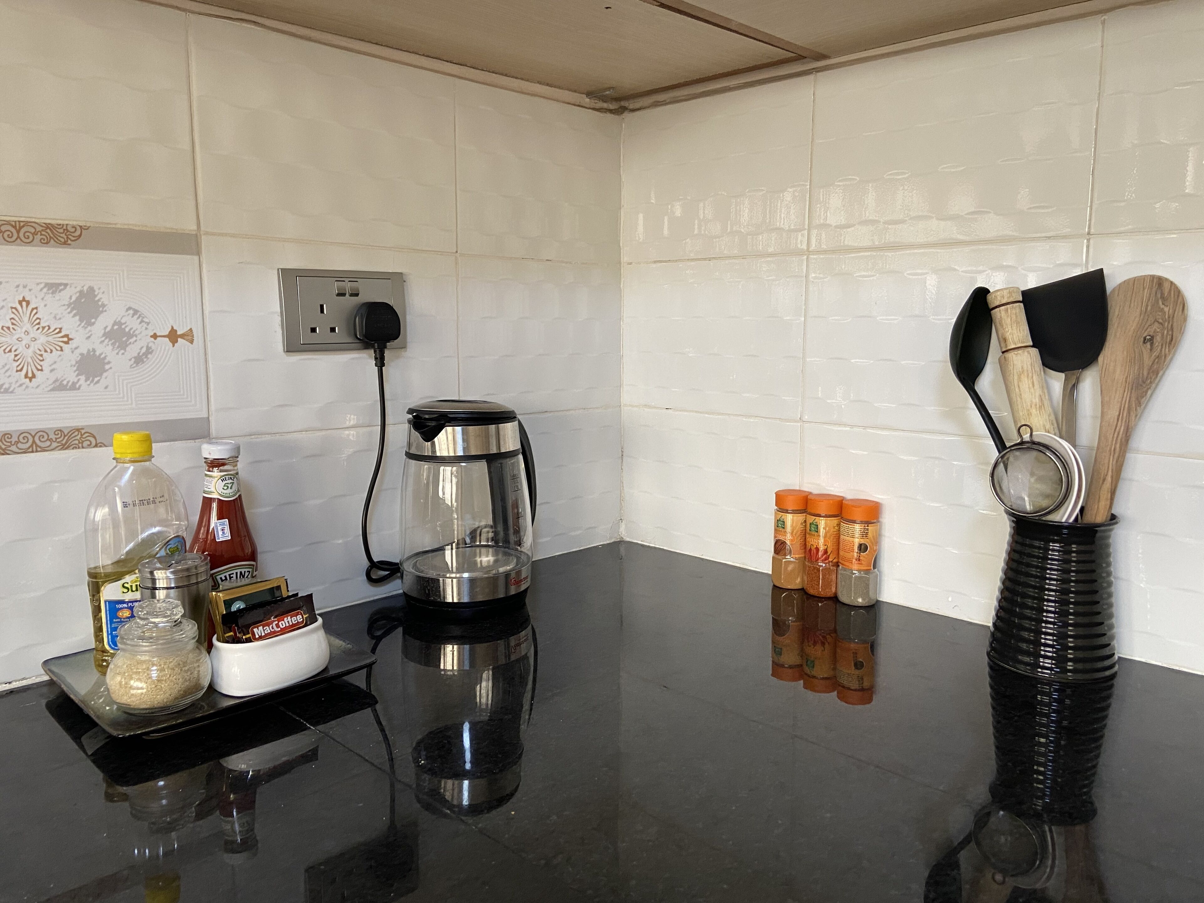 A kitchen counter with a coffee maker, condiment bottles, a spice rack, and wooden utensils.