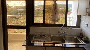 A kitchen with a large window, a sink, and a drying rack. - Midtown C32 Executive Suites (Nakuru)