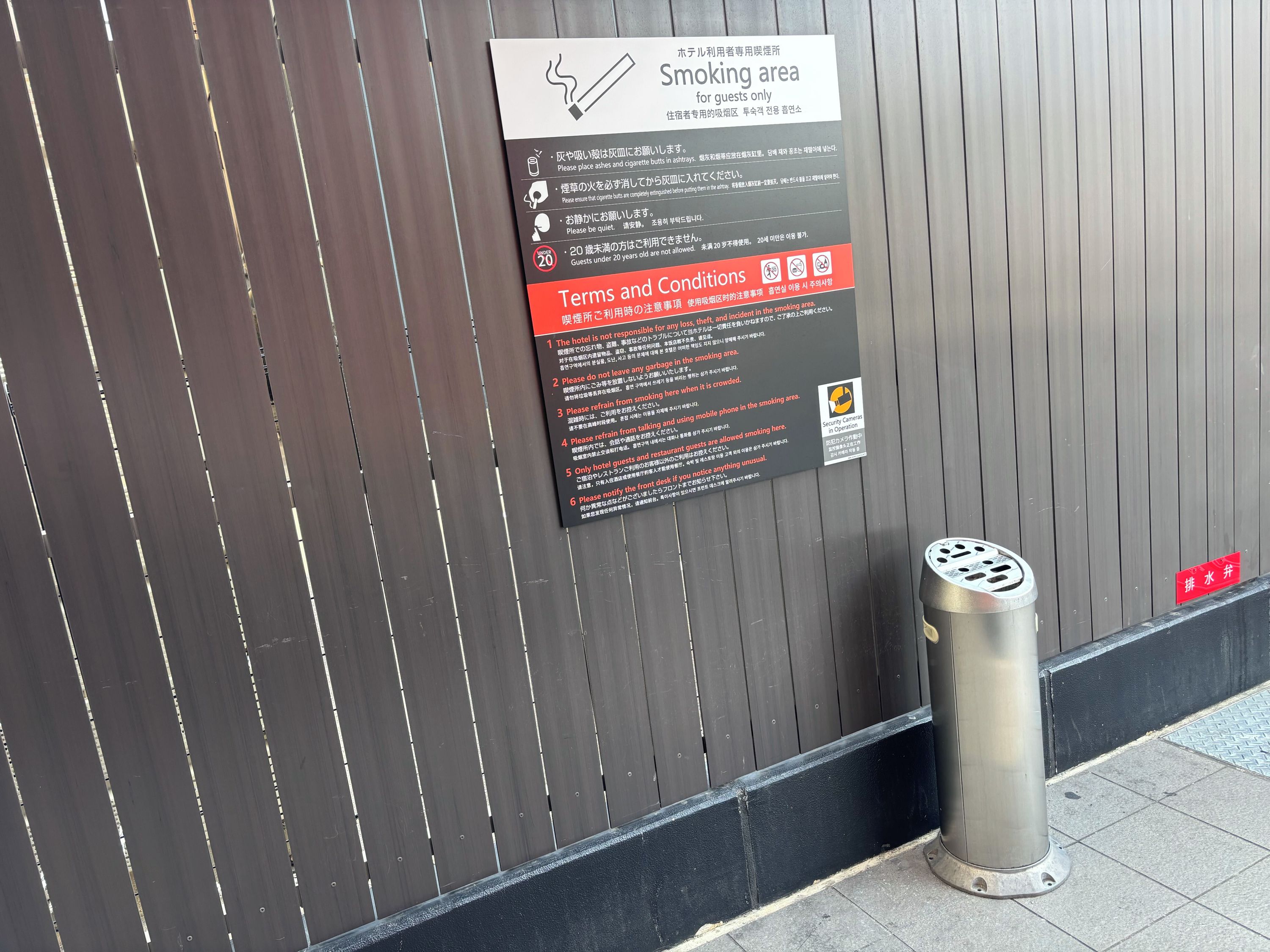 A sign indicating a smoking area for guests only, with terms and conditions listed.