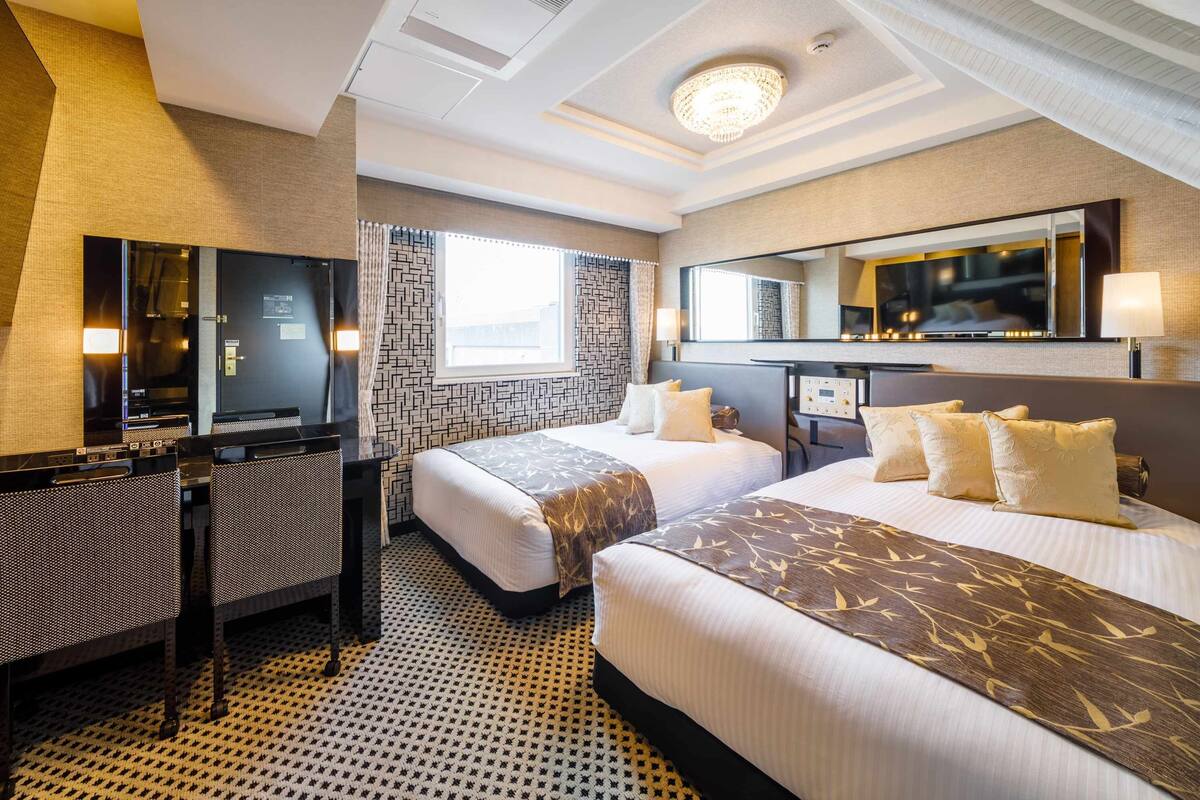 Une chambre d’hôtel avec deux lits, un bureau, une télévision et un grand miroir.