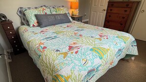 Un dormitorio con cama, mesita de noche, cómoda y puerta.