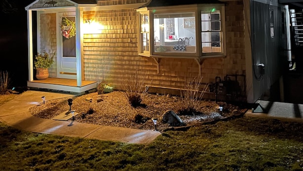 Una casa de dos pisos con un porche delantero, un garaje y un pequeño jardín.