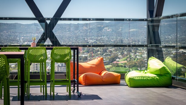 Terraza alta con mesa, sillas y pufs, con vista a la ciudad.
