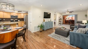 A modern kitchen with a dining area, a living room with a sofa and a TV, and a ceiling fan. - CASA BELLA - Stunning condo with sunset view. (Phoenix)