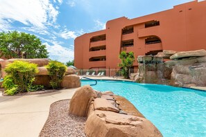 Ein Hotel mit Schwimmbad, umgeben von großen Steinen und Grünpflanzen.