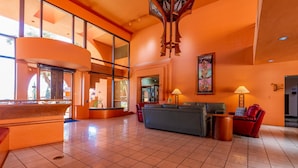 A spacious lobby with a large seating area, a wooden reception desk, and a high ceiling with a unique wooden light fixture. - CASA BELLA - Stunning condo with sunset view. (Phoenix)