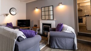 Una sala de estar con chimenea, televisión y dos sillones.