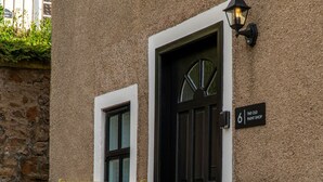 Un banco de madera frente a un edificio con una puerta negra y un letrero que dice 'The Old Paint Shop'.