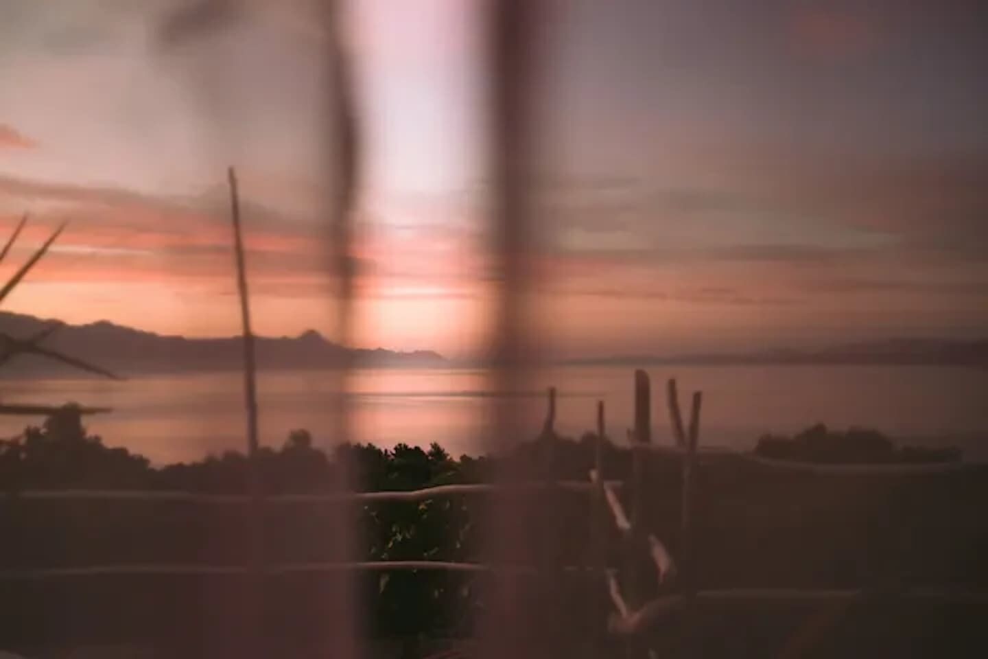 A view of a sunset over a body of water with distant mountains.