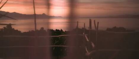 A view of a sunset over a body of water with distant mountains.