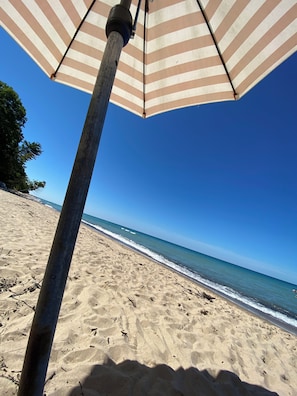 Relax in a designated seating area under a striped umbrella, overlooking the tranquil ocean with gentle waves.