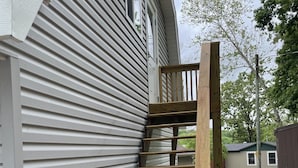 A wooden staircase leading up to a house with white siding.