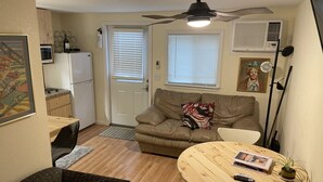 A compact living space with a kitchenette, a dining area, and a seating area with a sofa and a chair.
