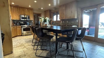 A modern kitchen with wooden cabinets, a central island, and a dining area with black chairs.