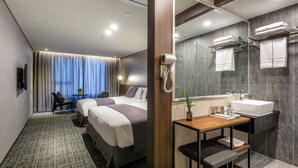 Une chambre d’hôtel avec deux lits, un bureau avec un lavabo et un miroir.