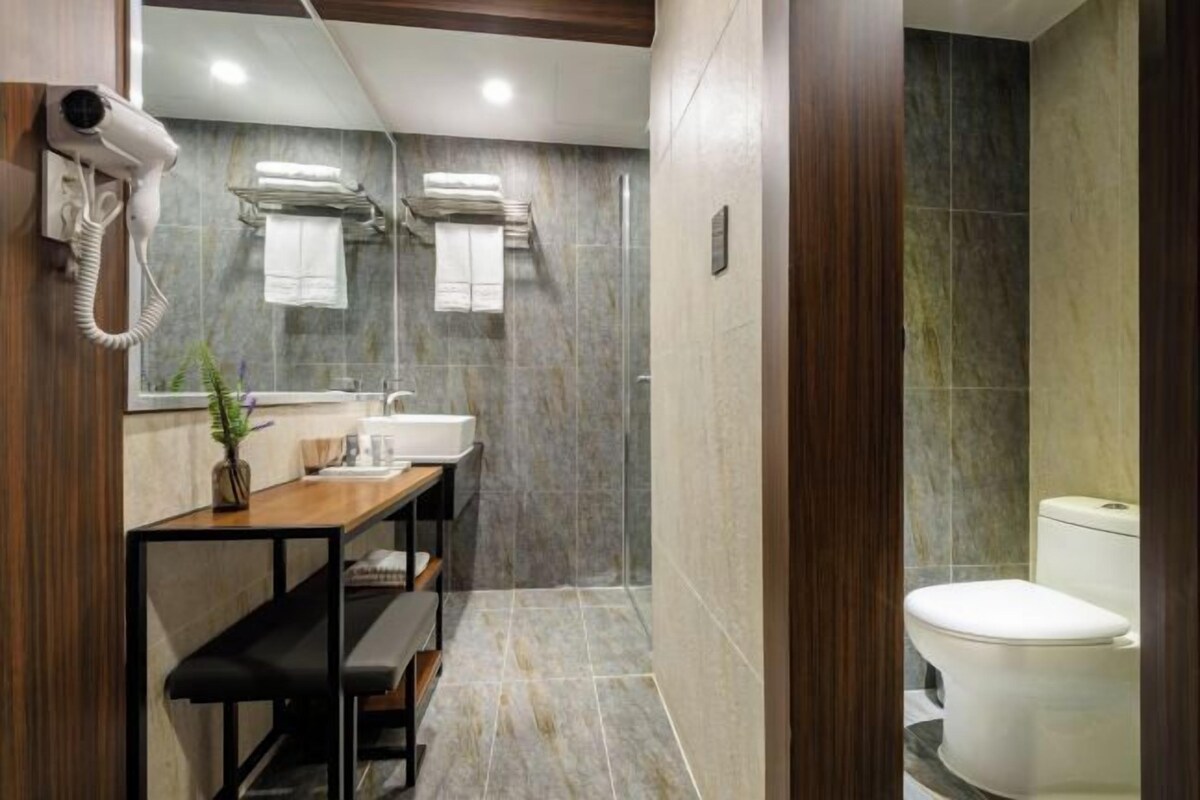 Une salle de bain moderne équipée d’une douche, de toilettes et d’un meuble-lavabo avec un miroir et un porte-serviettes.