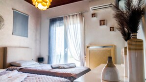 A bedroom with two beds, a bedside table, a lamp, a vase, and a window with curtains. - Villa Sar in Kampani Chania (Chania)