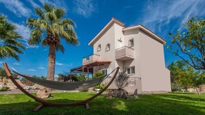 A two-story building with a balcony, a hammock, and a palm tree. - Villa Sar in Kampani Chania (Chania)
