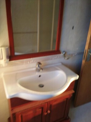 Un baño con lavamanos blanco, espejo y armarios de madera.