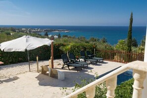 A terrace with outdoor seating, a white umbrella, and a view of the sea. - Pomos Harbourbiew Villa (Pomos)
