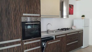 A modern kitchen with wooden cabinetry, a built-in oven, a gas stove, and a stainless steel range hood. - Holiday Home 10 Minutes From Porto Cesareo (San Pancrazio Salentino)