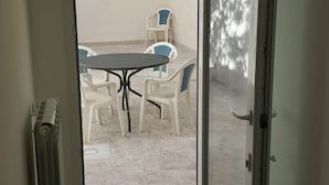A room with a sliding glass door leading to an outdoor patio area with a table and chairs. - Holiday Home 10 Minutes From Porto Cesareo (San Pancrazio Salentino)