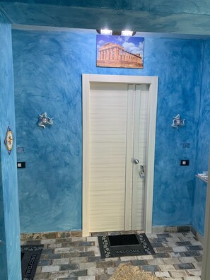 Comfortable room with a blue wall, white door, and framed artwork above, featuring decorative wall pieces and a tiled floor.