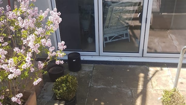A patio with potted plants, a sliding glass door, and a garden area visible through the door. - Lovely Large Garden Flat (Royal Tunbridge Wells)