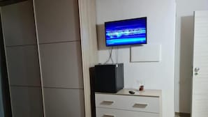 A bedroom with a bed, a TV on a stand, a wardrobe, and a door. - Room in B&B - B&b Villa Chiara Trappitello Taormina (Taormina)