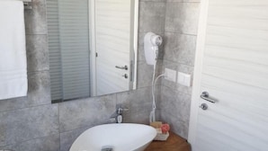 Ein Badezimmer mit einem weißen Waschbecken, einem Spiegel und einem Handtuch an der Wand.