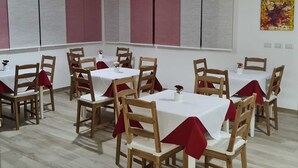 Ein Essbereich mit mehreren Tischen und Stühlen, die jeweils mit einer weißen Tischdecke und roten Stuhlabdeckungen versehen sind.