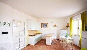 Kitchen with dining area, featuring a refrigerator, white cabinetry, and a tiled floor.