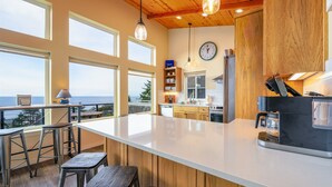 Una cocina moderna con una isla grande, techo de madera y ventanas amplias con vistas panorámicas.
