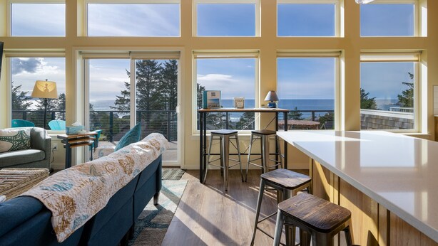 Una cocina moderna con ventanas amplias, una barra y vistas al océano.