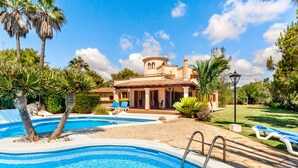 Une piscine, une maison, des palmiers et un ciel dégagé.
