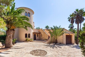 Un edificio con una torre redonda, un patio de piedra y palmeras.