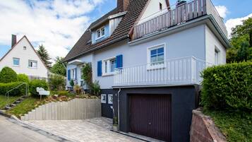 Ein zweistöckiges Haus mit Garage, Balkon und einer Treppe, die zum Eingang führt.