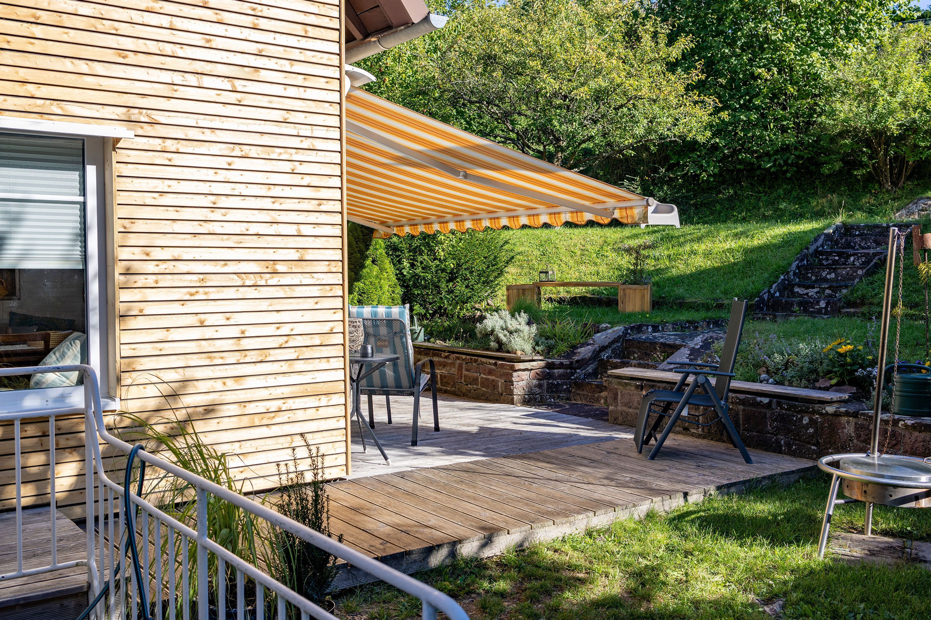 A wooden house with a patio, outdoor seating, and a small garden.