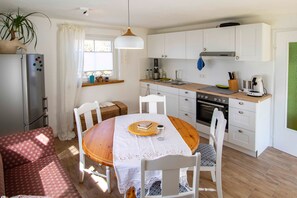 Une cuisine de taille réduite avec des meubles blancs, une table à manger en bois et un réfrigérateur.