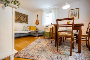 Un salon avec un canapé, des fauteuils, une guitare et un tapis à motifs.